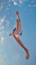 Low angle view of man jumping against blue sky