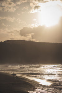 Silhouette man on beach against sky during sunset