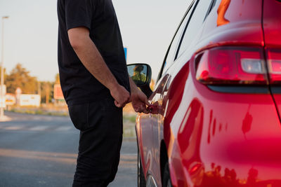 Midsection of man holding umbrella while standing in car