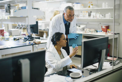 Female doctor discussing with male doctor in medical room seen through glass