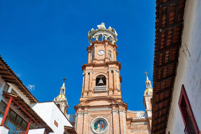 Low angle view of clock tower amidst buildings against sky