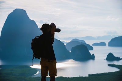 Man photographing at camera against sky