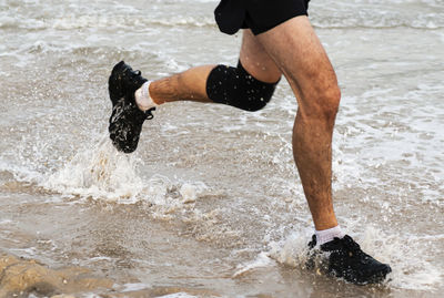 Low section of man running on shore