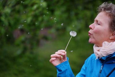 Portrait of man holding dandelion on field