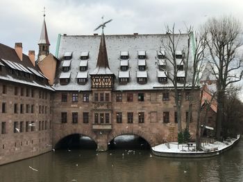 Bridge over river by buildings in city against sky