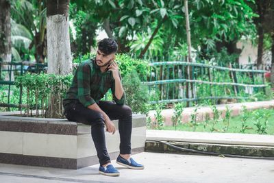 Full length of young man sitting outdoors