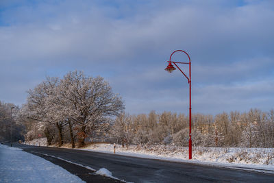 Road amidst trees on field against sky during winter