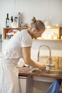 Young worker washing hands in sink at crockery workshop
