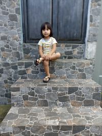 Full length of young woman standing against wall