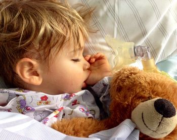 Close-up of cute baby sleeping in bed with teddy bear
