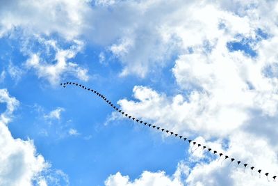 Low angle view of kites flying against sky