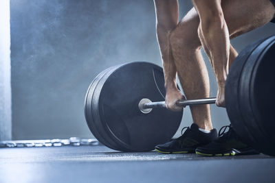 Close-up of man doing deadlift exercise at gym