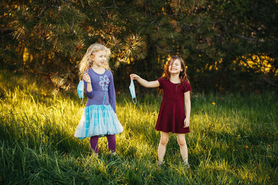Smiling friends with masks standing on grass
