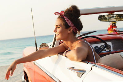 Side view of young woman sitting at beach