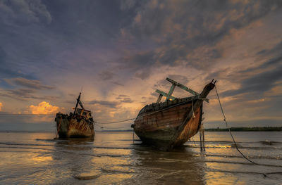 Abandoned ships against sunset sky