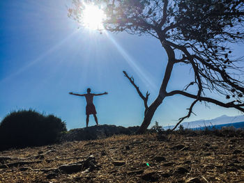 Low angle view of silhouette man standing by tree against sky