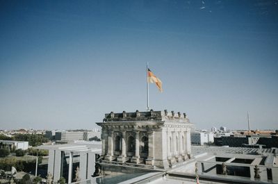 Low angle view of flags against clear blue sky