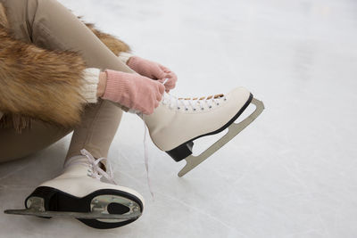 Low section of woman wearing ice skate on snowy land