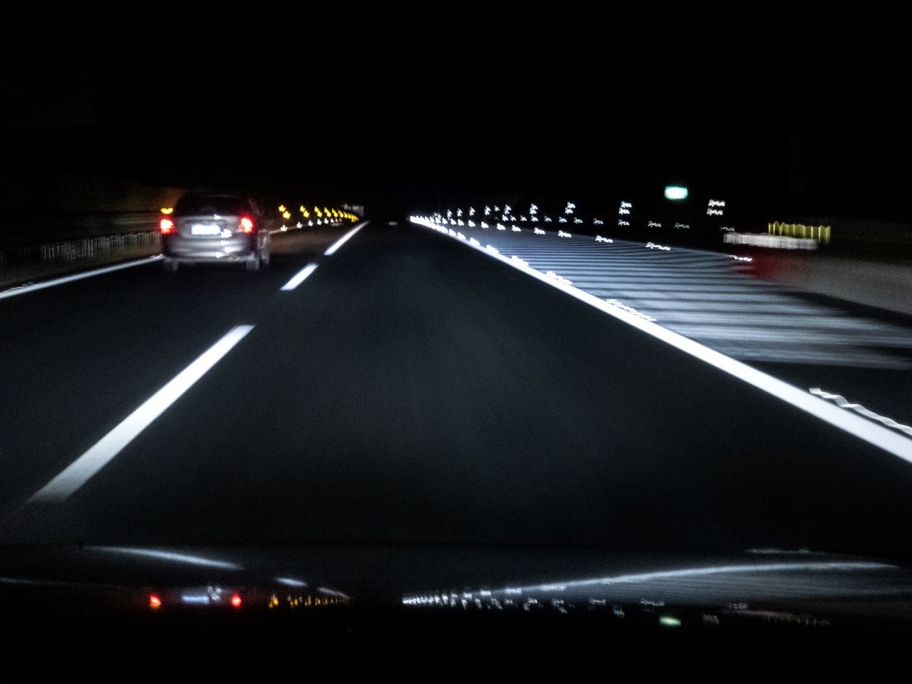 CARS ON ILLUMINATED ROAD AT NIGHT