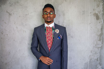 Portrait of well-dressed young man standing against wall