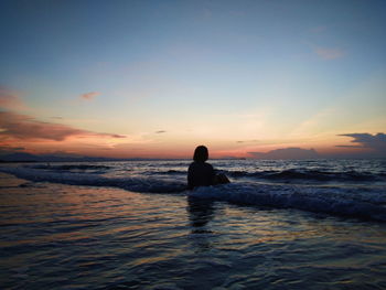 Silhouette man on beach against sky during sunset