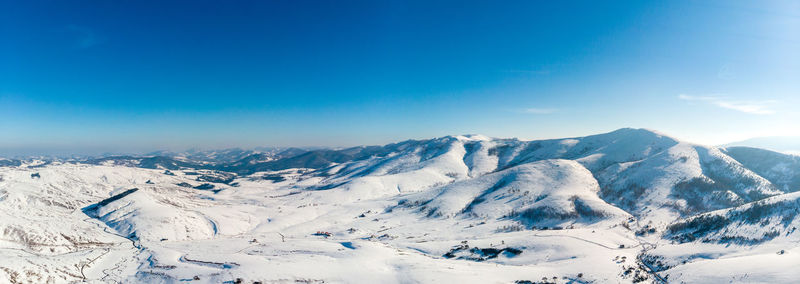 Scenic view of snowcapped mountains against blue sky