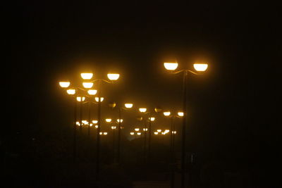 Illuminated street light against sky at night