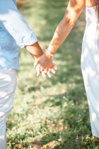 Couple hold hands in a vineyard at sunset