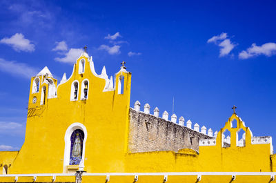 Low angle view of yellow church against blue sky