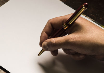 Close-up of hand holding paper against white background