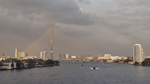 City at waterfront against cloudy sky