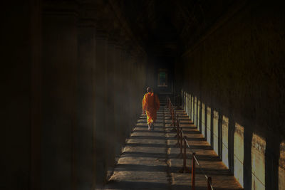 Rear view of man walking in corridor of building