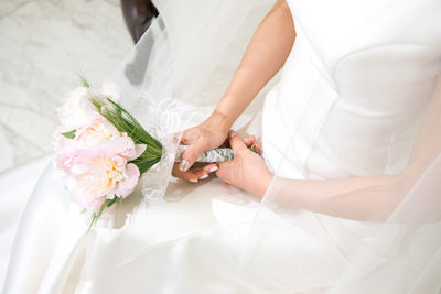 Midsection of bride holding bouquet