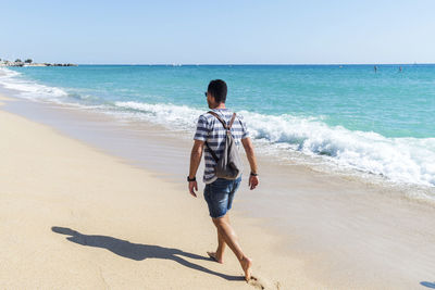 Full length of man walking at beach against sky