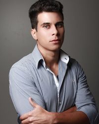 Portrait of young man with arms crossed against gray background