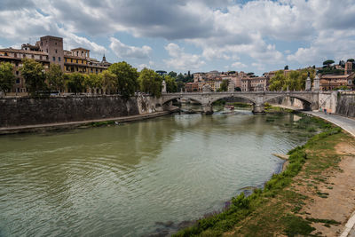 Arch bridge over river against cloudy sky