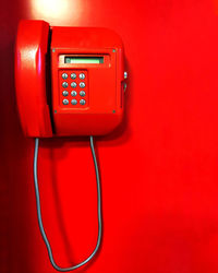 Close-up of red telephone on wall