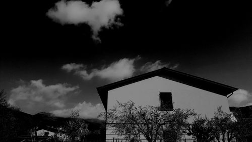 Low angle view of silhouette trees and building against sky