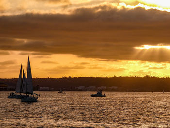 Silhouette sailboat sailing on sea against sky during sunset