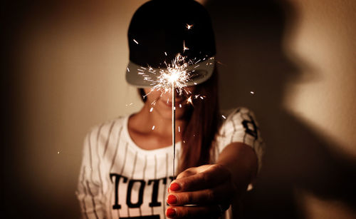 Woman holding sparkler indoors