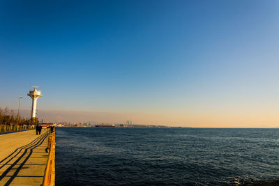 Street by sea against clear sky during sunset