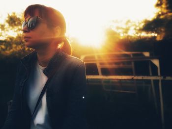 Close-up of young woman against sun during sunset