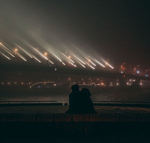 Rear view of silhouette people against illuminated sky at night