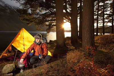 Man preparing hot drink at simple camp in the british lake district