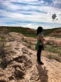 Rear view of woman standing on landscape against sky