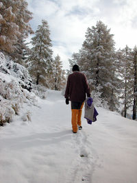 Rear view of man walking on snow