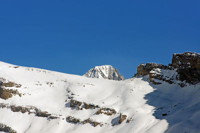 Low angle view of snow covered mountain against blue sky