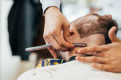 A barber cuts the beard of a man with a razor in a barbershop