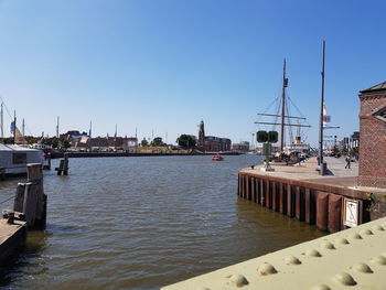 Sailboats moored in harbor against clear blue sky