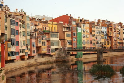 Buildings by river against sky